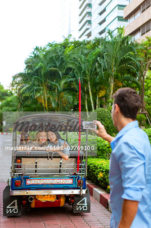 Man taking photo of friends in auto rickshaw