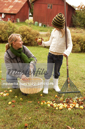 Mother with daughter picking apples in garden