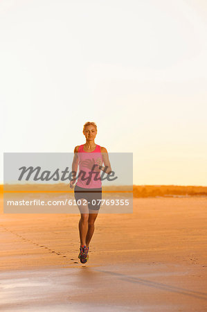 Woman running on beach at dusk