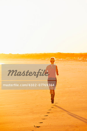 Woman running on beach at dusk