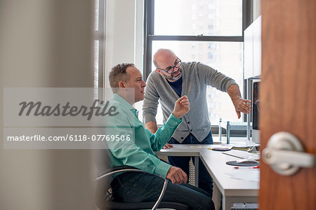 Two men in an office looking at a computer screen.