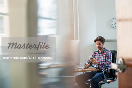 View through an office partition of a man seated at a desk.