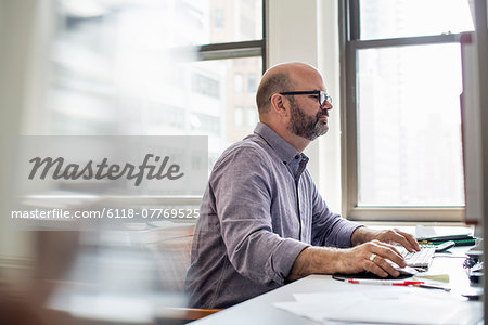 Office life. A man sitting at a desk using a computer, looking intently at the screen.