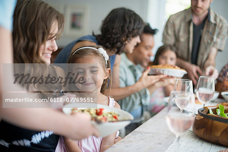 A family gathering for a meal. Adults and children around a table.