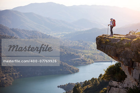 Female hiker standing on cliff and enjoying valley view