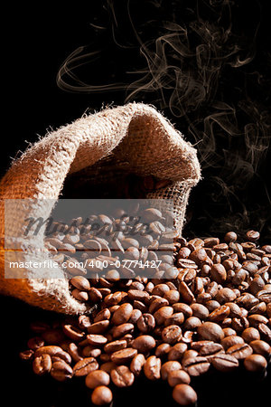 Aromatic coffee background. Fresh roasted coffee beans in brown natural sack isolated on dark background.