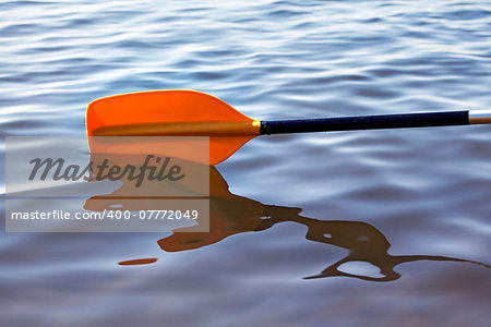 Kayak paddle on side of a boat at still river water