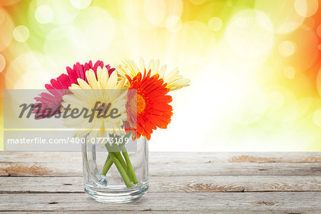 Colorful gerbera flowers on wooden table with autumn sunny bokeh