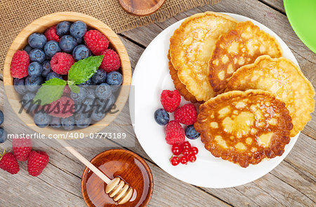 Pancakes with raspberry, blueberry, mint and honey syrup. On wooden table