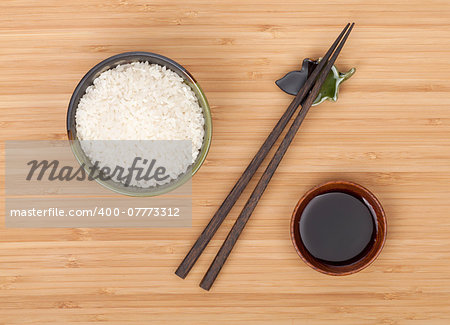 Rice bowl, chopsticks and soy sauce over bamboo table