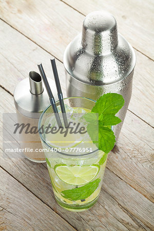 Fresh mojito cocktail and bar utensils on wooden table