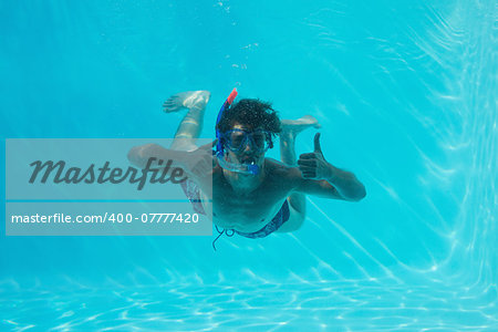 Young man wearing snorkel underwater while gesturing thumbs up