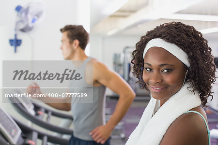 Fit woman smiling at camera on treadmill at the gym