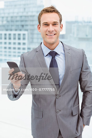 Portrait of smart young businessman holding mobile phone in office