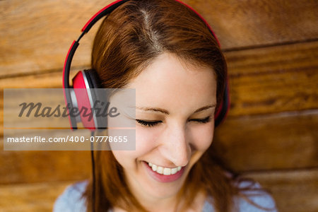 Natural smiling redhead listening to music with closed eyes in the city