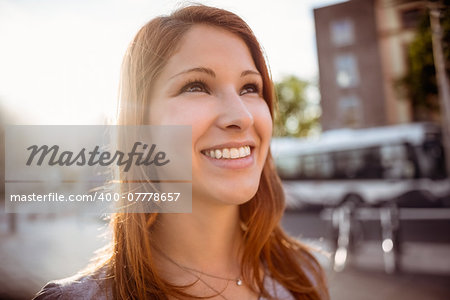 Smiling pretty redhead on a sunny day in the city