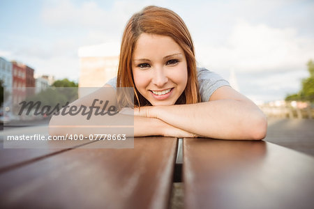 Portrait of a smiling redhead lying on bench in the city