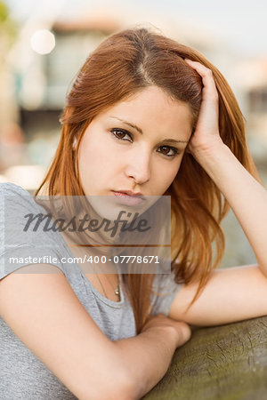 Sad redhead frowning at camera in the city