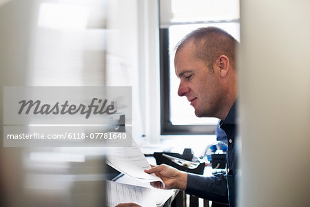 A man working in an office, reading paperwork.