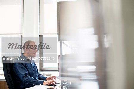 A man working in an office at a desk using a computer mouse. Focusing on a task.