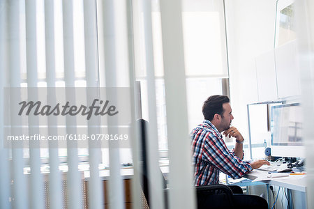 A man working in an office, focusing on a task. Using a computer keyboard and screen.