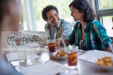 A group of friends eating at a diner. A couple seated side by side. A group of friends eating at a diner. A couple seated side by side.