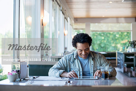 A man sitting in a diner using a digital tablet.
