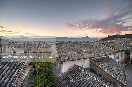 The sun is about to rise over the roofs and mountains of Lijiang Old Town, UNESCO World Heritage Site, Lijiang, Yunnan, China, Asia