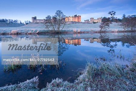 Alnwick Castle reflected in the River Aln on a frosty winter morning, Northumberland, England, United Kingdom, Europe