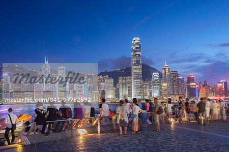 Tourists looking at Hong Kong Island skyline from Tsim Sha Tsui at dusk, Hong Kong, China, Asia