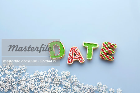 Overhead View of Letter Cookies spelling DATE on Blue Background with Snowflakes