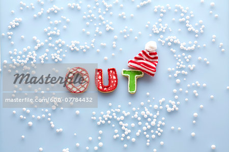 Overhead View of Sugar Cookies spelling OUT with Touque and Snow on Blue Background