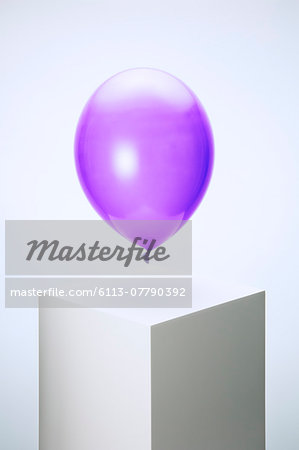 Purple balloon hovering over pedestal