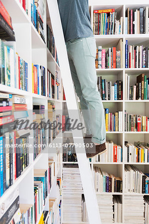 Man standing on ladder to reach books in library