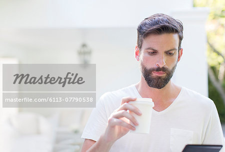 Man drinking coffee and using digital tablet