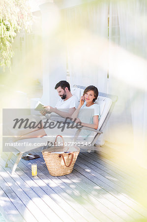 Couple relaxing in lawn chairs on wooden deck