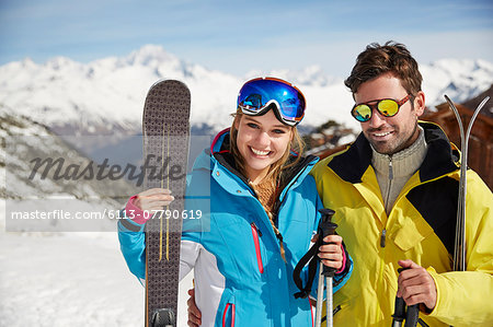 Couple carrying skis on mountain top