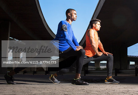 Men stretching before exercising on city street