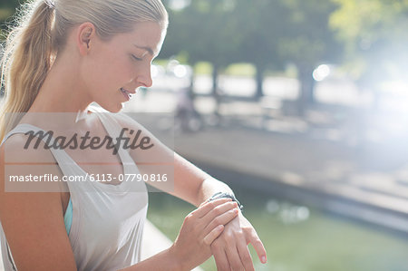 Woman looking at watch before exercising on city street