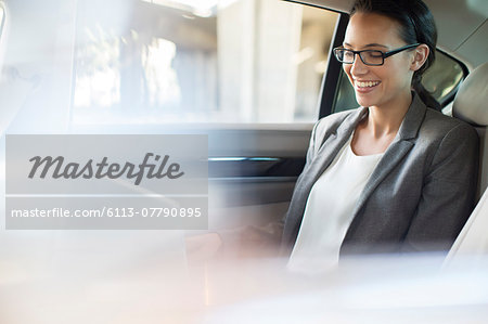 Businesswoman using laptop in car back seat