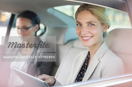 Businesswoman using digital tablet in car back seat