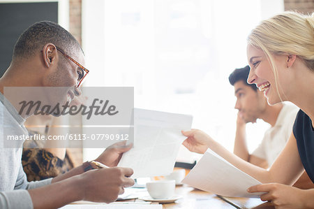 Business people looking through paperwork together in cafe