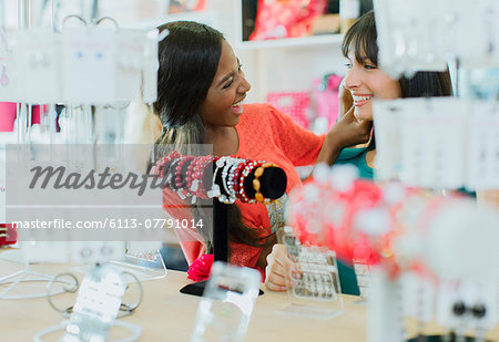 Women trying on jewelry together in clothing store