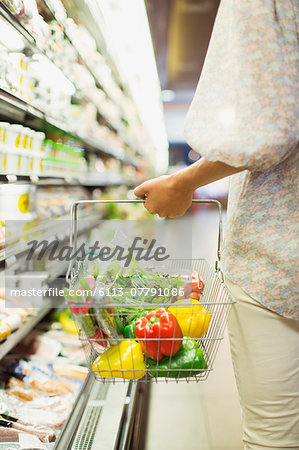 Woman carrying full shopping basket in grocery store