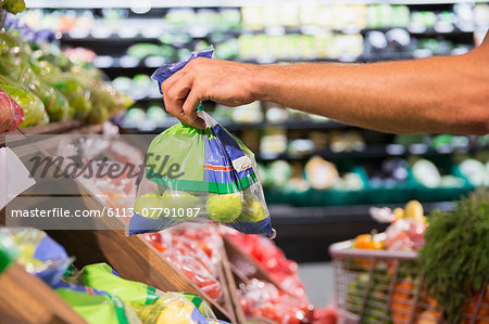 Man holding bag of produce in grocery store