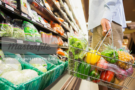 Man carrying full shopping basket in grocery store