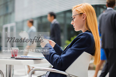 Businesswoman using cell phone at table outside