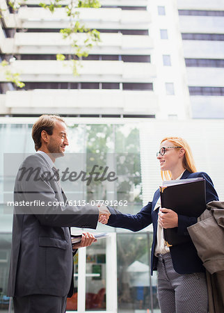 Business people shaking hands outside of office building