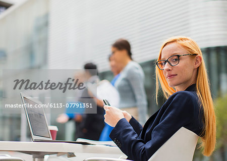 Businesswoman working at table outside of office building