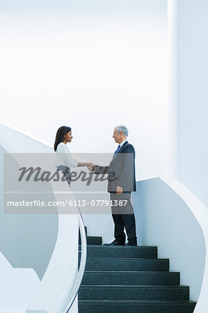 Business people shaking hands on stairs of office building